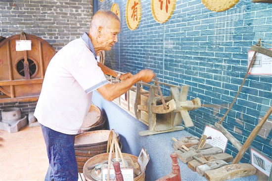 新華村打造農(nóng)耕文化展館，留住鄉(xiāng)村記憶。圖為村中老人向記者介紹農(nóng)具。