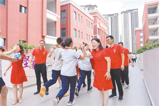 蓬江區(qū)紫茶中學(xué)的領(lǐng)導(dǎo)和老師們與考生們擊掌，為他們加油、鼓勁。