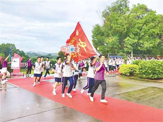 在臺(tái)山市武溪中學(xué)，老師揮舞著“中考加油”的紅旗為考生加油助威。