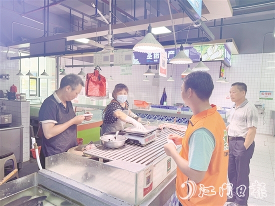 買菜易的平臺(tái)接單員李叔（橙色馬甲）正在魚攤旁等待取單。