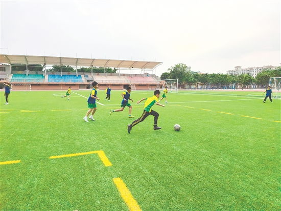 大課間時間，同學(xué)們在全新升級的體育場上踢足球。